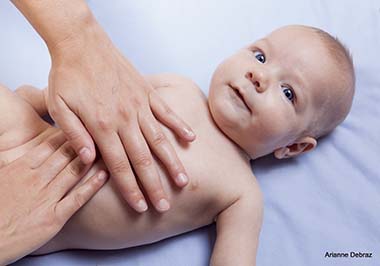 Three month baby boy receiving abdomen massage from a female massage therapist